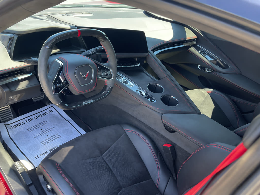 Cleaned sports car interior with black leather, red contrast stitching, and a protective floor mat